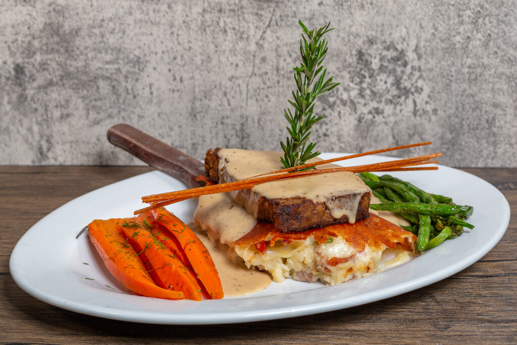 The Art of the Perfect Brunch at Hash House A Go Go, The Plaza 1 A beautifully plated meatloaf dish at Hash House A Go Go, showcasing the art of comfort food with creamy sauce, grilled vegetables, and a rosemary garnish.
