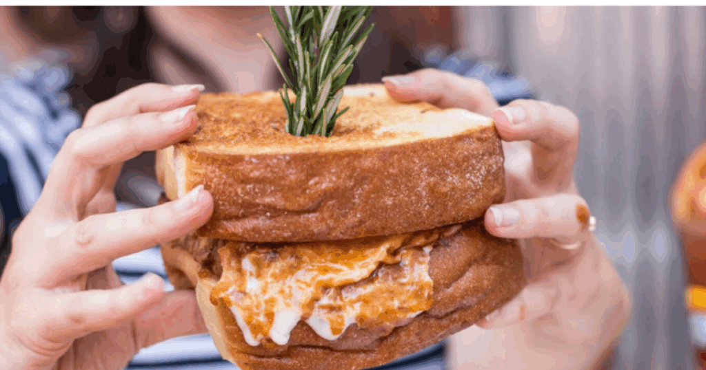 Behind the Scenes: Meet the Chefs of Hash House A Go Go at The Plaza 1 Massive comfort food sandwich crafted by the chefs at Hash House A Go Go, garnished with rosemary and loaded with savory flavor.