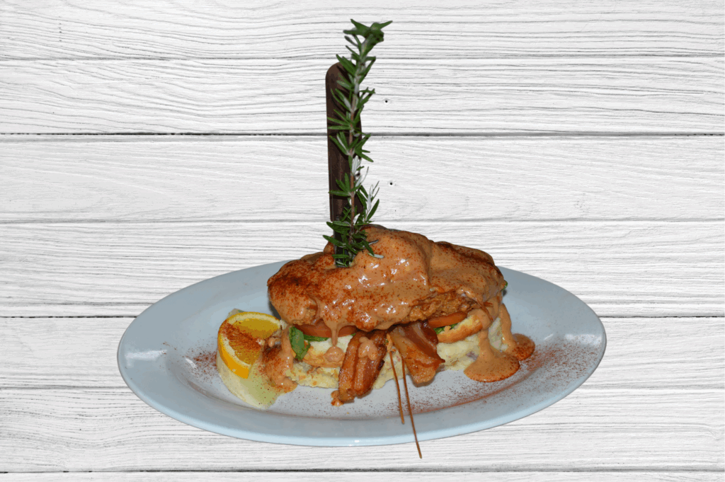 For comfort food lovers: crispy fried chicken benedict topped with creamy sauce, stacked with bacon and fresh tomato over mashed potatoes.